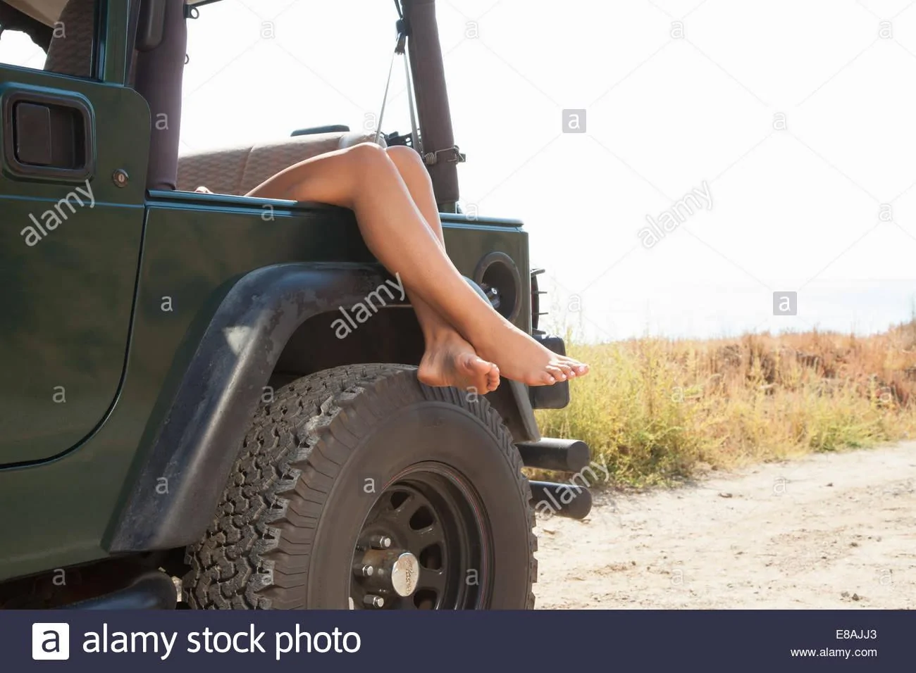 legs-of-young-woman-resting-over-jeep-window-malibu-california-usa-E8AJJ3.webp