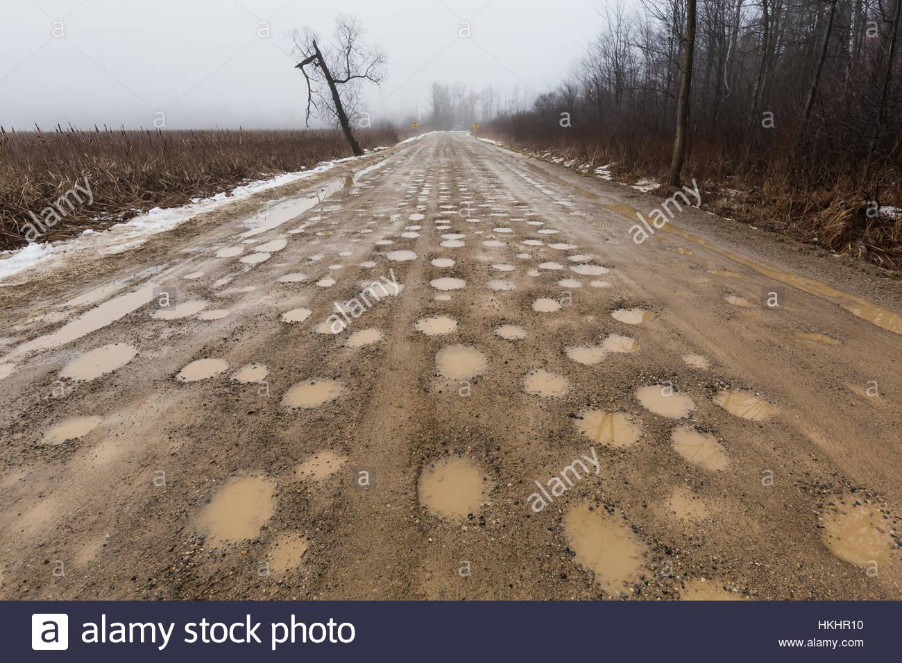 sand-road-with-potholes-during-a-january-thaw-in-central-michigan-HKHR10.jpg